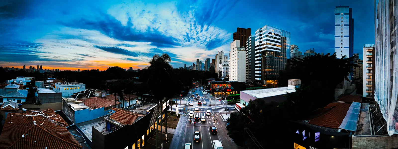 Panorâmica de avenida de São Paulo na hora azul, com prédios iluminados