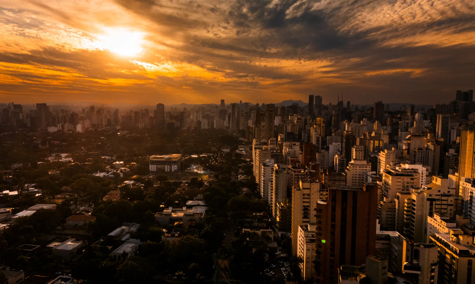 Vista aérea de São Paulo ao pôr do sol com o céu alaranjado