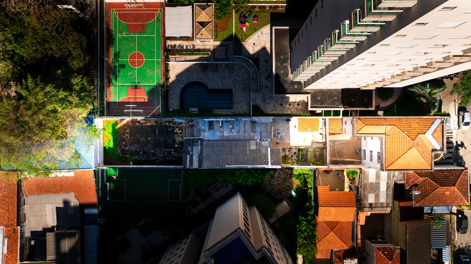 Vista zenital de quadra urbana com áreas de lazer e telhados