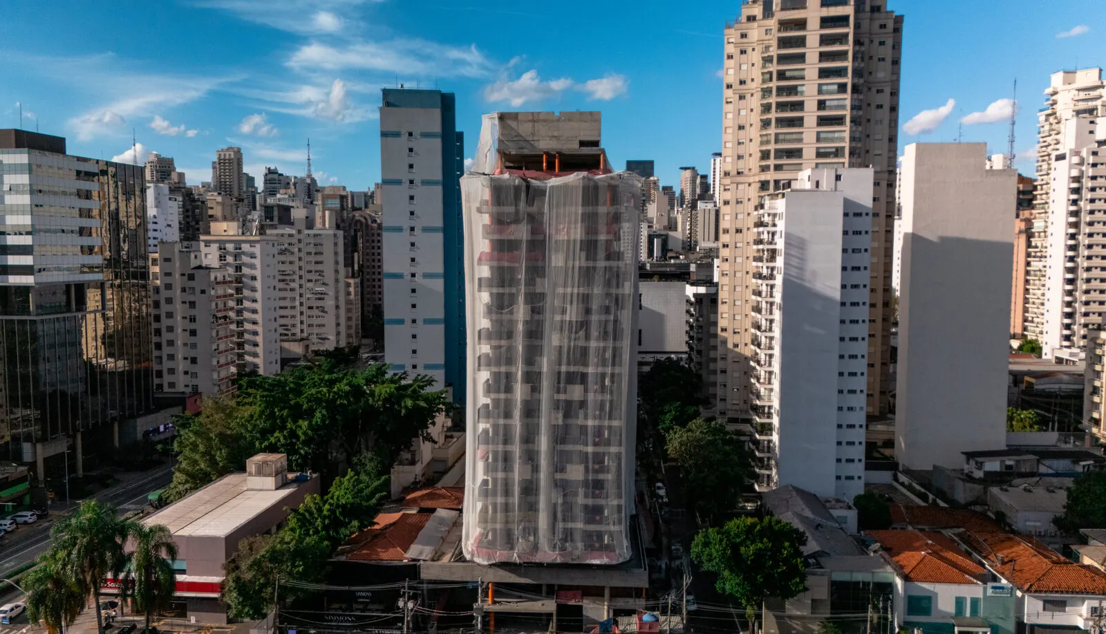Prédio em construção entre edifícios residenciais, imagem aérea