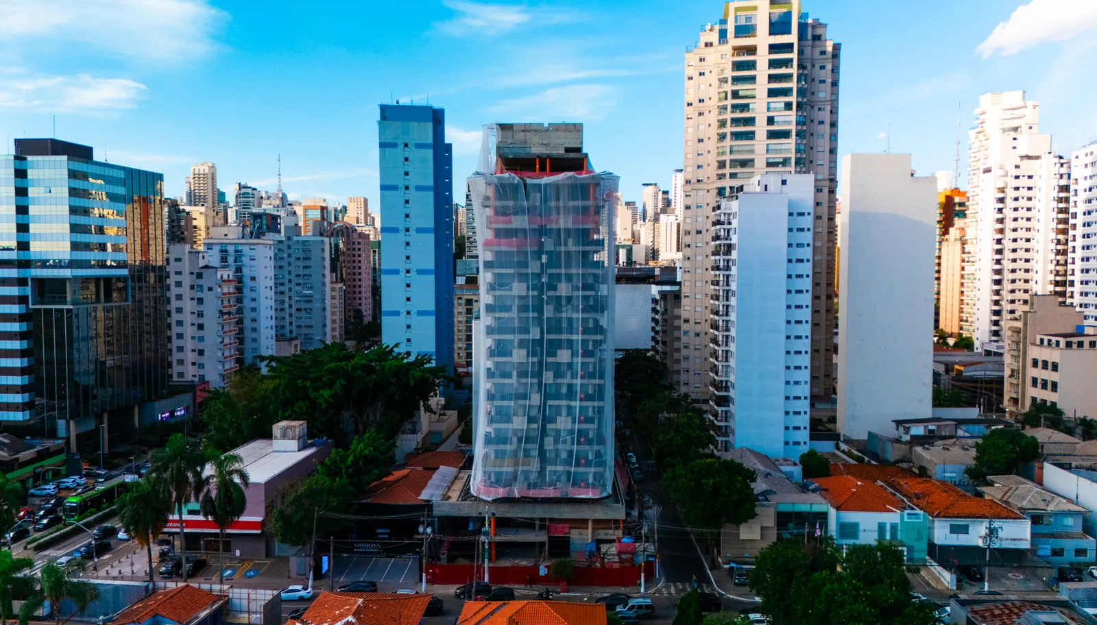 Torre residencial em construção envolvida em tela de proteção, vista de drone em São Paulo