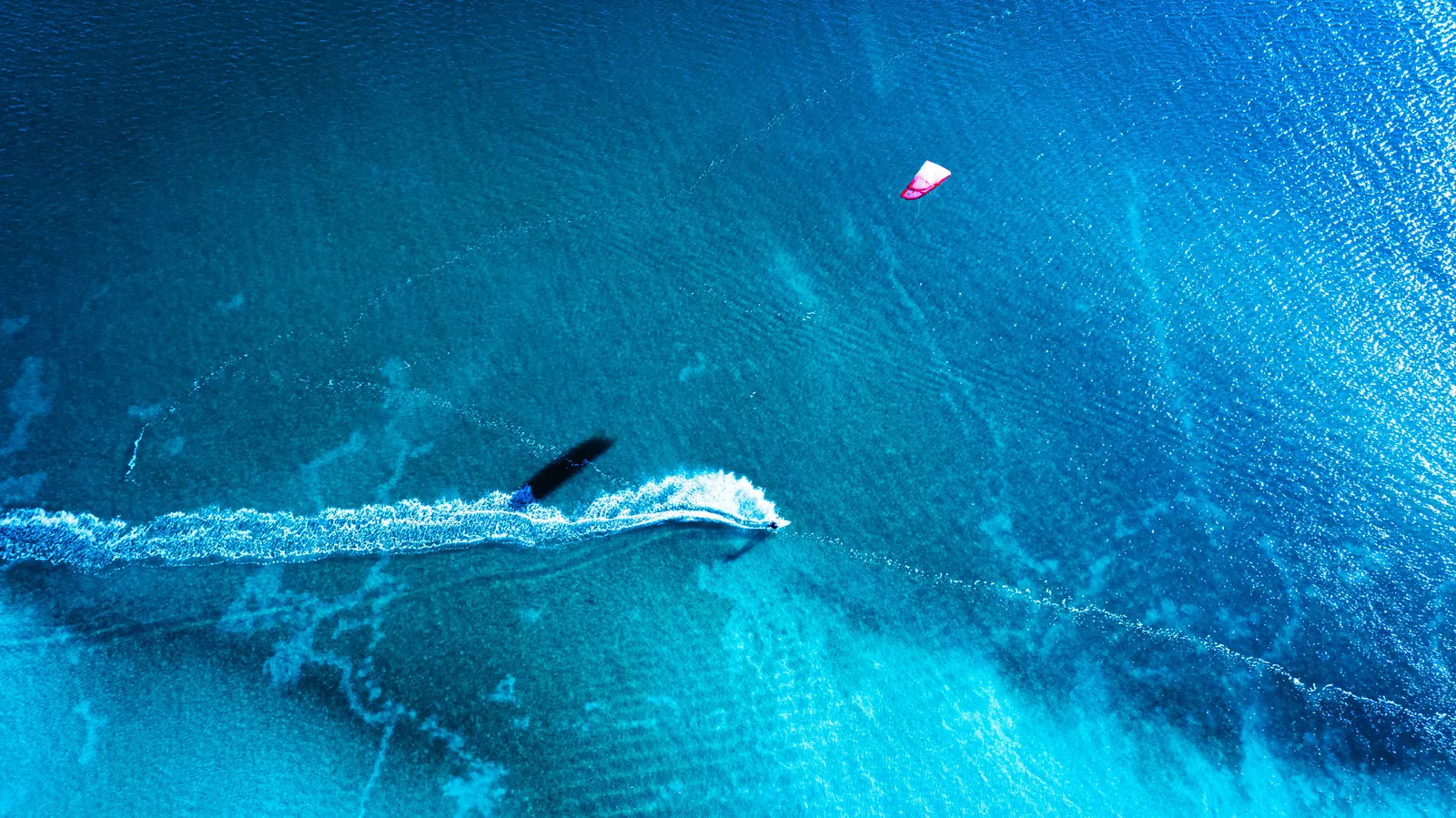 Vista zenital de kitesurf sobre água azul-turquesa