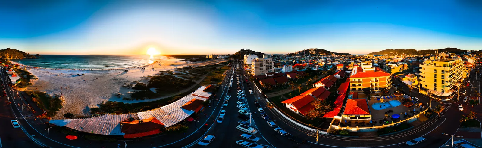 Panorâmica aérea de orla e cidade litorânea no fim de tarde
